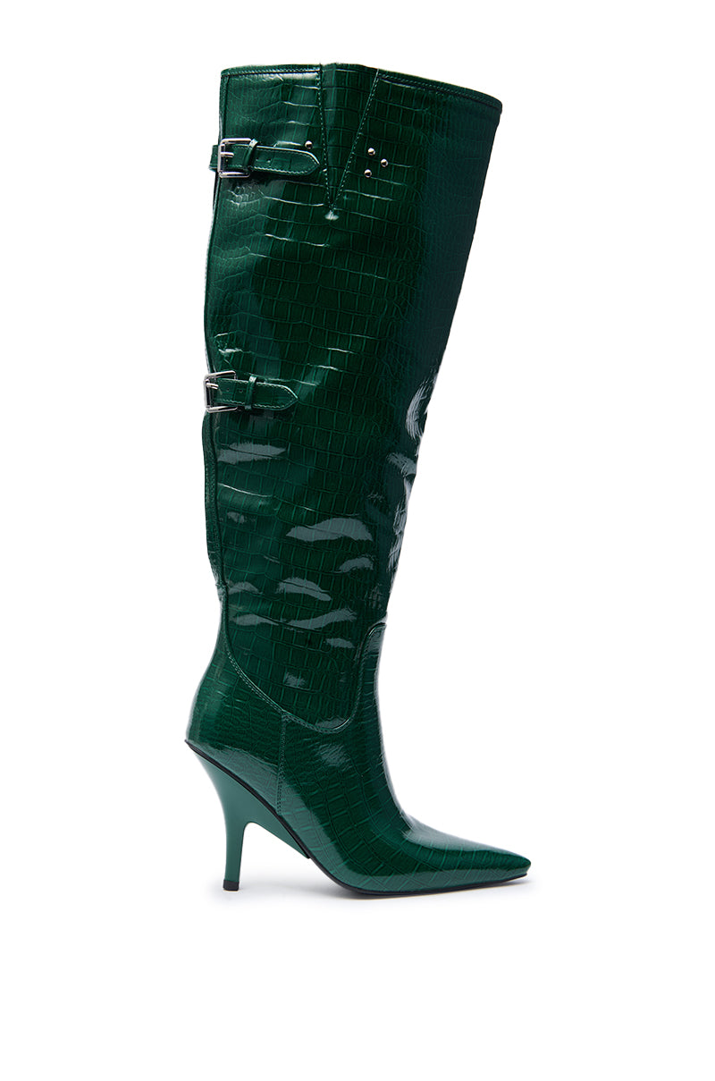 The AZALEA WANG GESINE GREEN CROC PATENT LUXE BOOT is a tall, glossy green knee-high boot with a pointed toe, stiletto heel, croc-embossed pattern, and two silver buckles near the top.