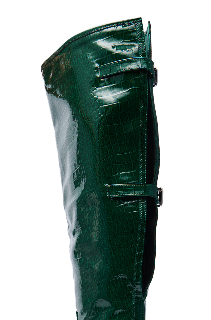Close-up of the AZALEA WANG GESINE GREEN CROC PATENT LUXE BOOT—a shiny, dark green croc-embossed knee-high boot featuring a stiletto heel and two side buckles.
