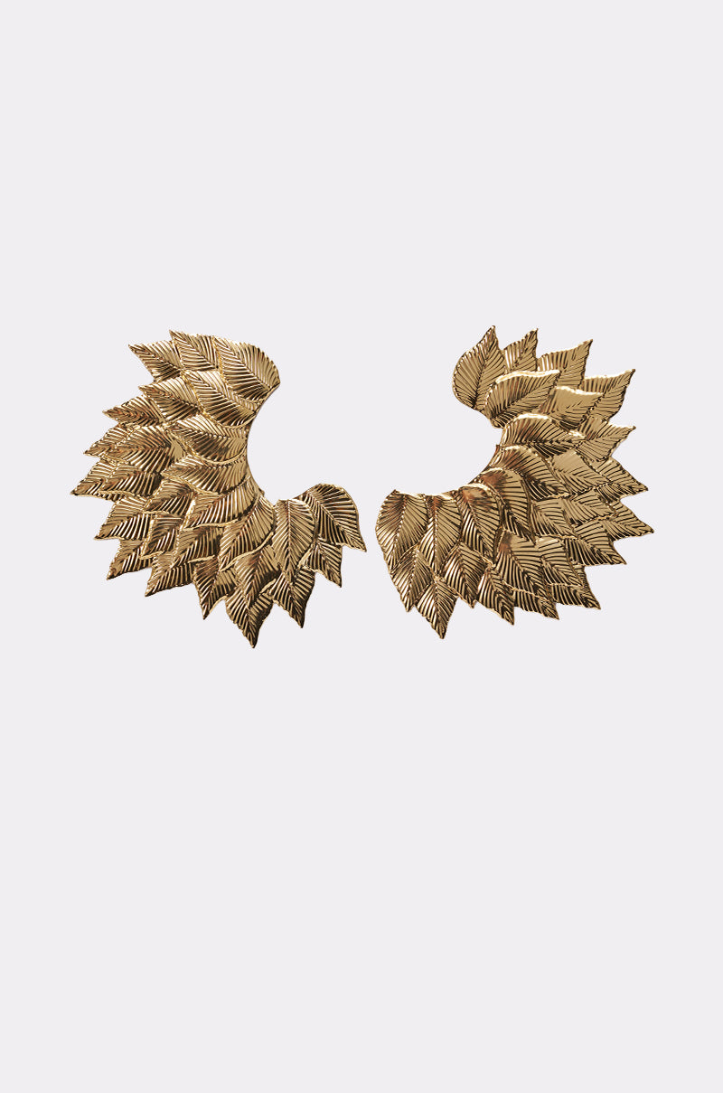 The SUNSHINE EARRING features gold leaf statement earrings with layered, overlapping feather-like shapes that fan out boldly, resembling wings, set against a plain white background. 0