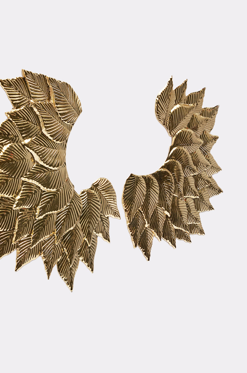 The SUNSHINE EARRING wall decor features two gold, wing-like forms crafted from overlapping textured leaves, arranged to face each other on a plain white background and evoking the look of bold statement earrings. 3