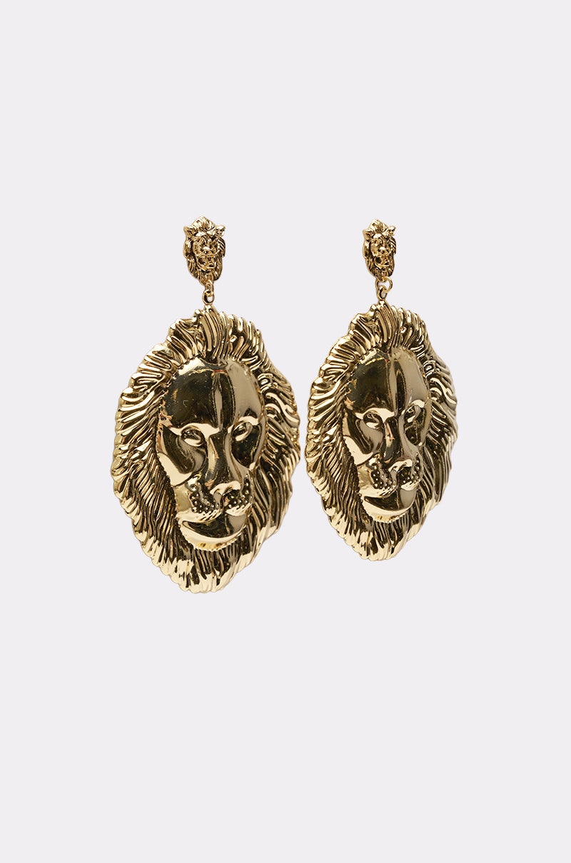 The ROAR EARRING features gold-tone lion head earrings with detailed manes, hanging from small round studs, shown against a plain white background. 2