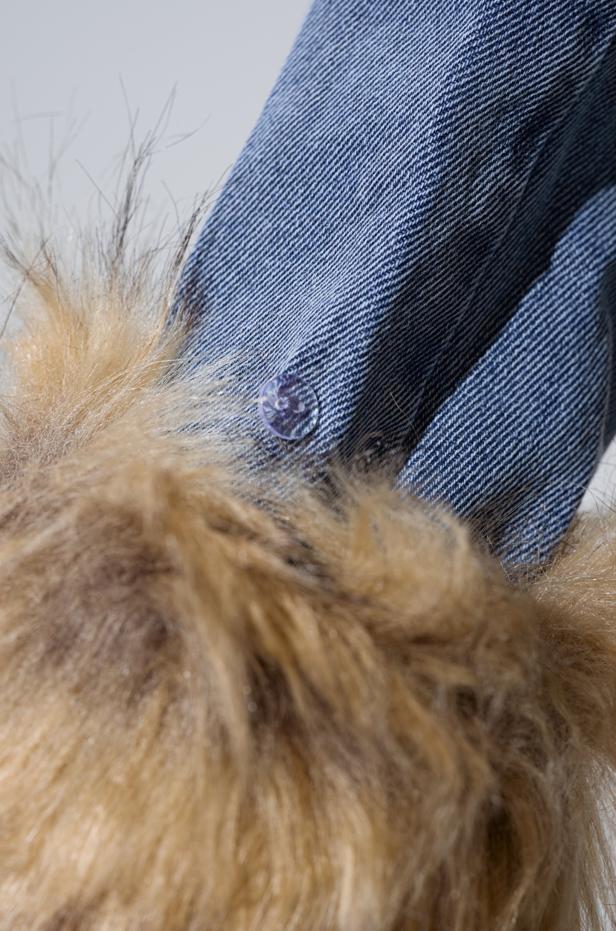 Close-up of blue denim and a metal snap button beside brown faux fur, capturing the playful vibe of the NEW GISELE CROPPED FUR TRIM JACKET in true Bratz Doll style.