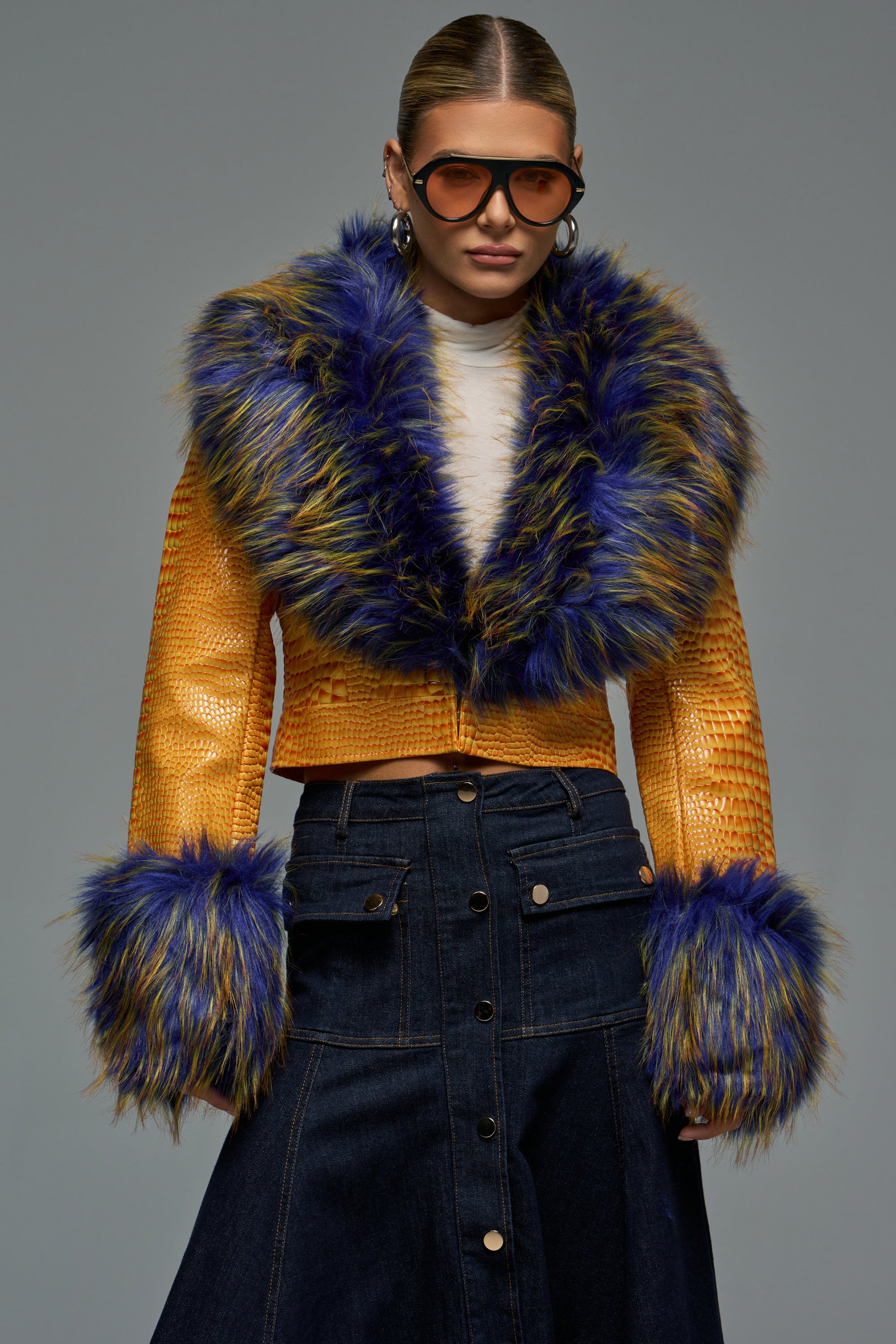 The GISELE FUR TRIM MOTO IN MULTI CROC is a cropped yellow faux leather moto jacket with a crocodile-embossed texture and blue faux-fur trim on the collar and cuffs.