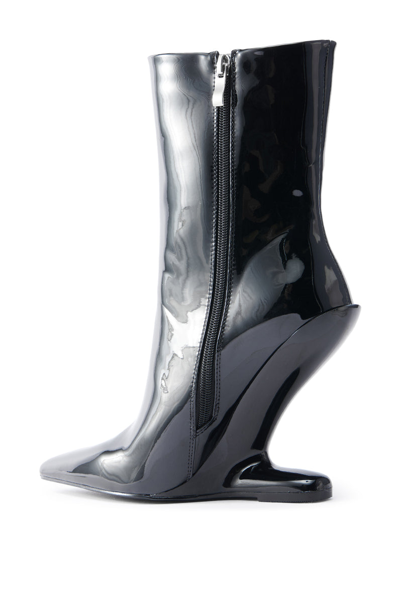 The AZALEA WANG GLACIELLE PATENT BLACK WEDGE BOOTIE is a glossy black high-heeled bootie with a pointed toe, featuring a curved inverted wedge heel and side zipper. The faux patent leather offers a shiny finish that enhances its unconventional angular silhouette.