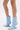 Wearing the AZALEA WANG GLACIELLE BLUE WEDGE BOOTIE with a pointed toe, sculptural wedge heel, and side zippers, a person stands against a white backdrop.