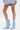 A person wearing a light blue denim jacket and the AZALEA WANG GLACIELLE BLUE WEDGE BOOTIE with sculptural wedge heels stands against a plain white background, revealing only their legs and part of the jacket.
