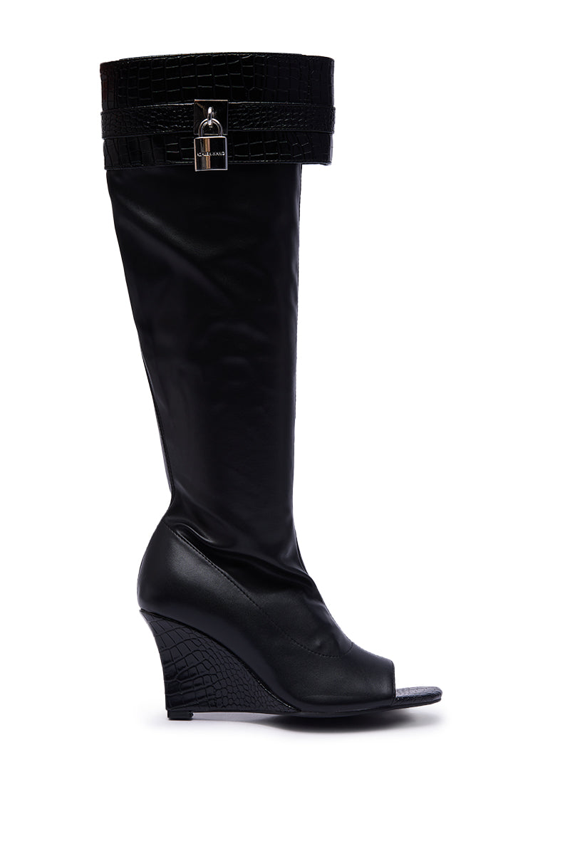 The AZALEA WANG GLENNA BLACK STRETCH PU WEDGE BOOT features luxe faux leather, a peep toe, crocodile-textured top and heel, and a decorative upper calf strap with a silver buckle for a chic, modern look.