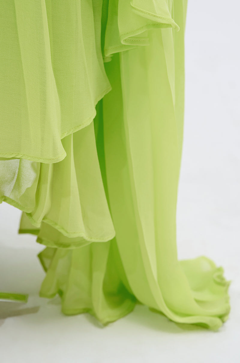 Close-up of the NIXEN MAXI DRESS WITH CHIFFON OVERLAY: sheer, light green chiffon draped in soft layers against a white background. Lightweight and slightly translucent—ideal for elegant maxi or evening wear.