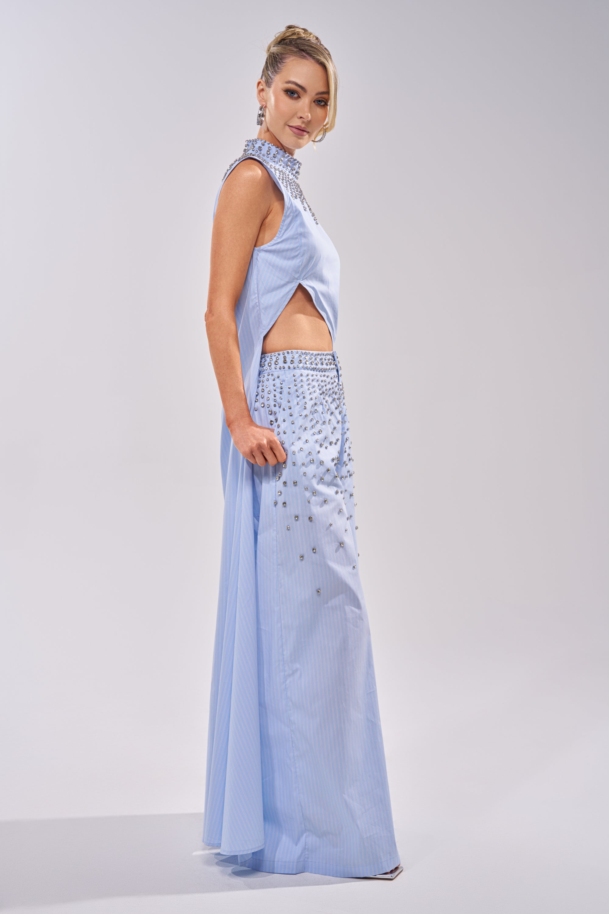 A woman poses gracefully against a simple, light background wearing the STAR OF THE NIGHT POPLIN BLOUSE, styled with her hair up. 3