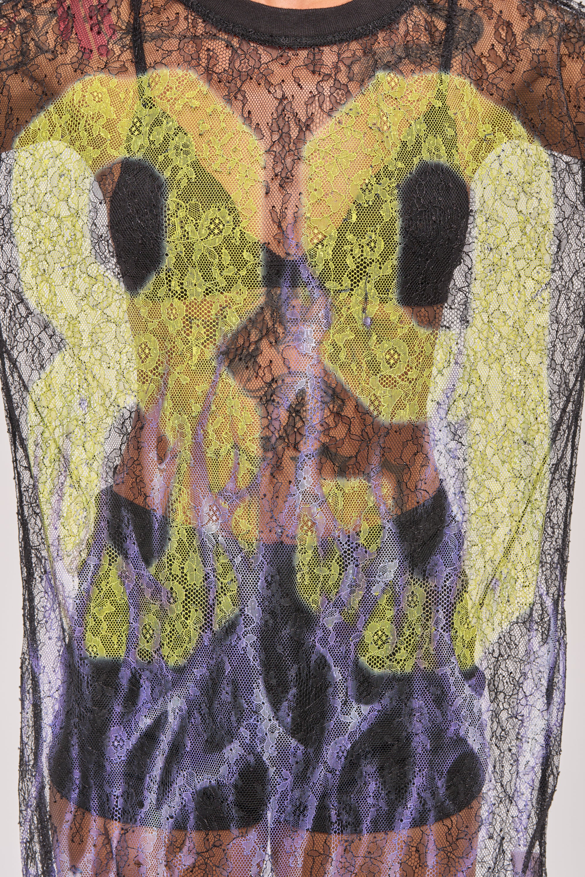 A close-up of the ALL THE RAGE LACE JERSEY MINI DRESS—a black lace mini dress with a bold abstract graphic of yellow shapes and purple flames—styled for an edgy streetwear look. 7