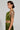 A person with short, dark hair is wearing the METALLIC DREAM BLOUSE and reveals a tattoo of a woman's face on their arm along with a numeric tattoo on their waist. They pose in profile, highlighting an asymmetrical silhouette against a plain background.