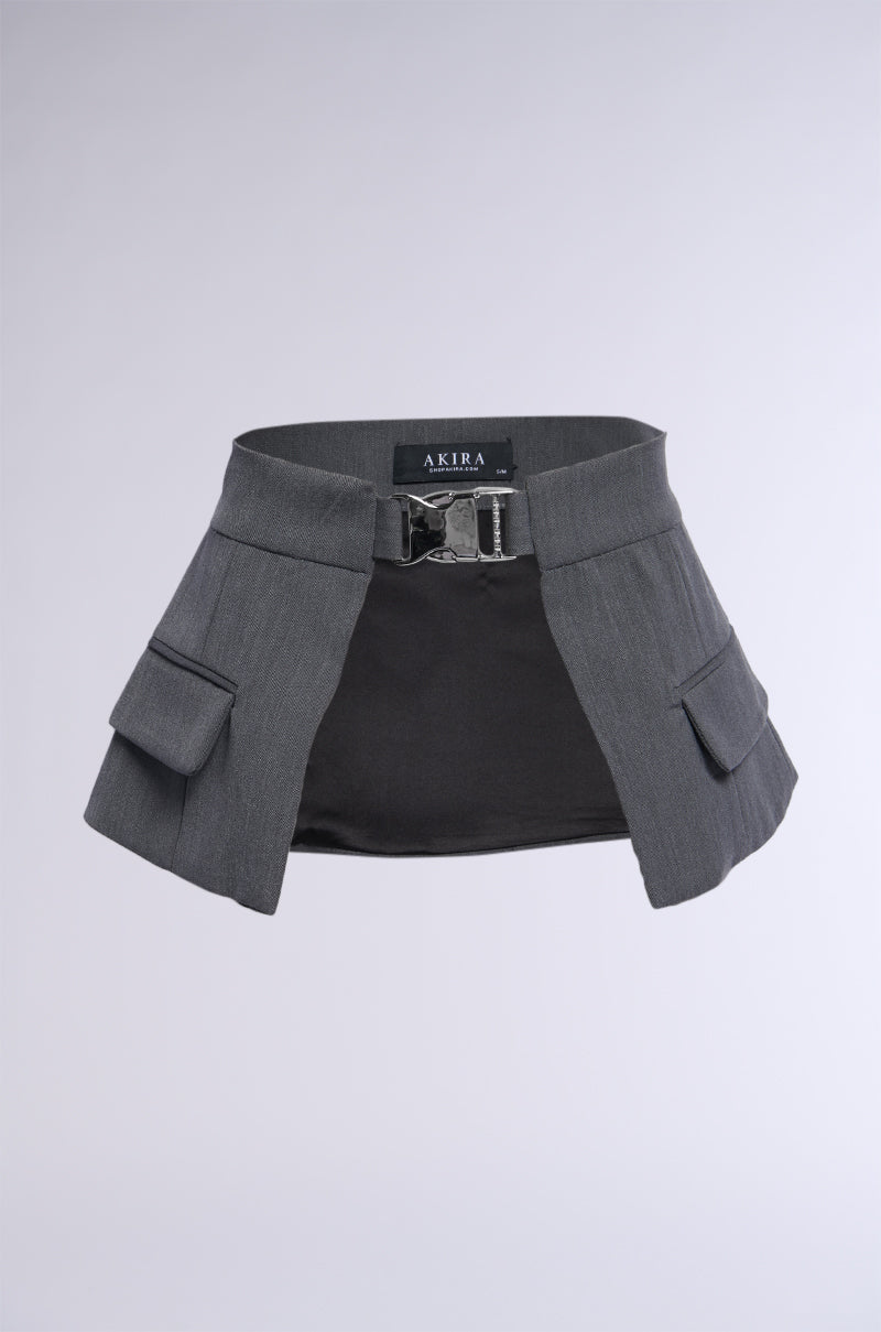 A textured dark grey mini wrap skirt, labeled with the "UTILTY CHIC BELT" on the waistband tag. It boasts a metallic silver buckle front closure and two side flap pockets, all set against a plain background.