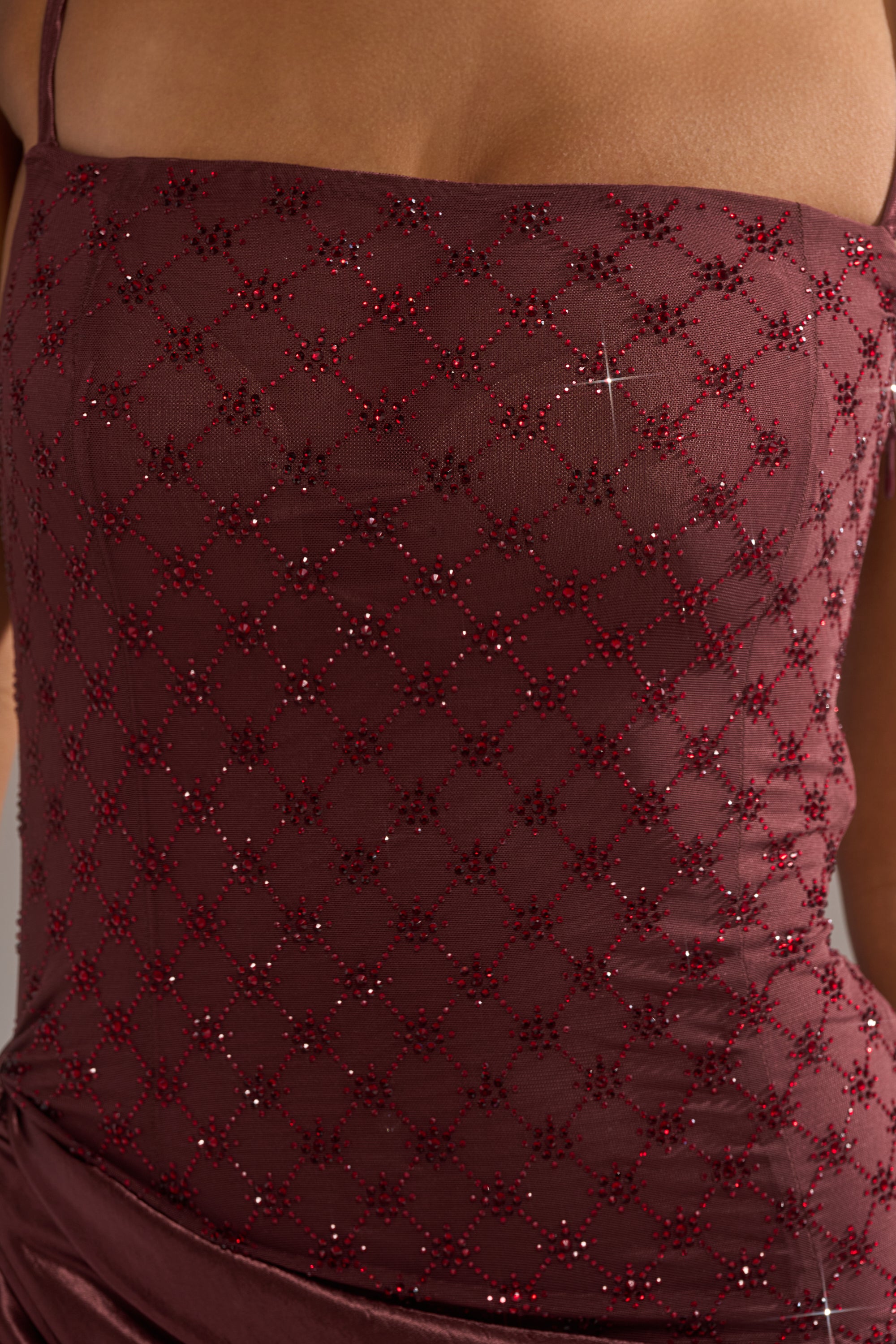 Close-up of a person wearing the RUNAWAY SATIN MESH MAXI DRESS, featuring thin straps and maroon fabric adorned with red and silver sequin geometric patterns for a sparkling, elegant night-out look.