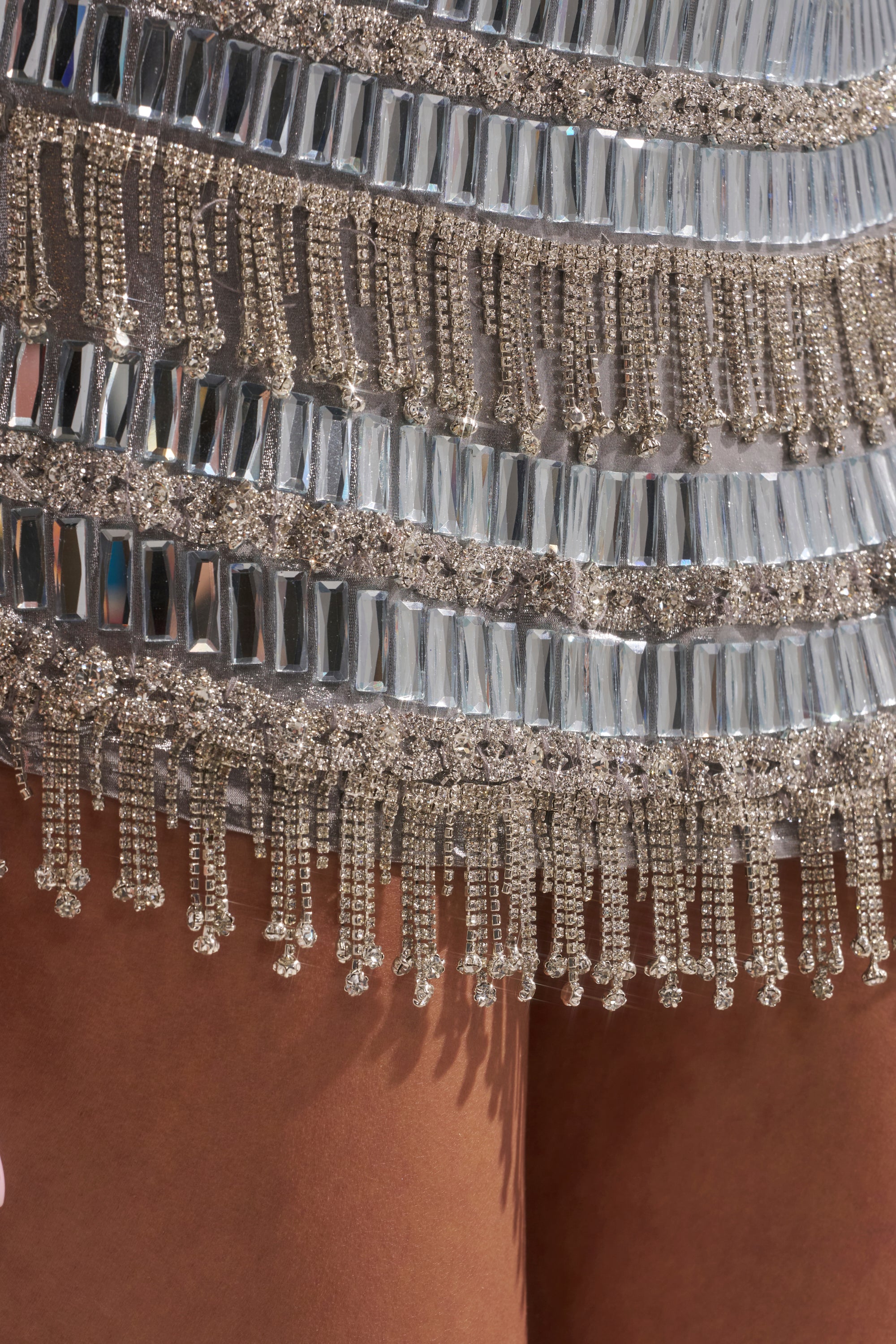Close-up of the CHANDELIER RHINESTONE MINI DRESS detailed with silver rhinestones, sequins, and metallic fringe, revealing a peek of brown fabric or skin beneath—an ideal choice for standing out at any party.