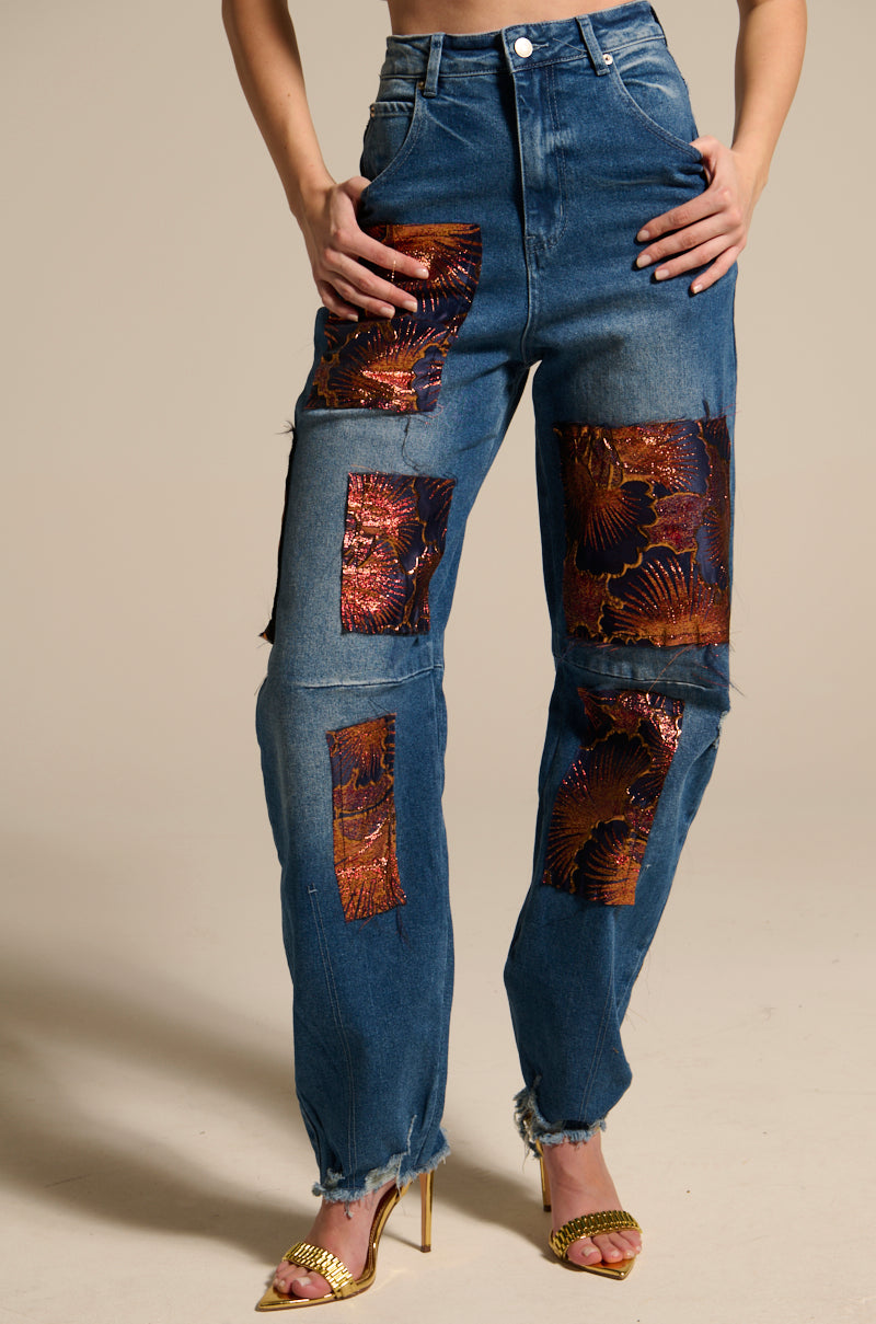 Wearing ELEGANT VIBES BROCADE PATCH RELAXED DENIM featuring floral metallic patches and frayed hems, styled with gold high-heeled sandals. The upper body is not visible.