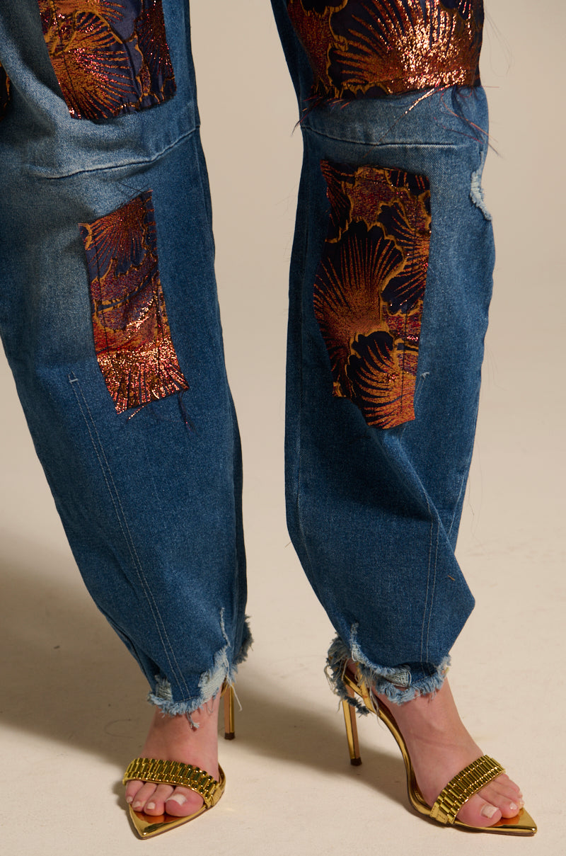 Wearing ELEGANT VIBES BROCADE PATCH RELAXED DENIM—high-rise, distressed blue jeans with gold and copper shell-pattern and floral metallic patches—paired with gold braided-strap high-heeled sandals.