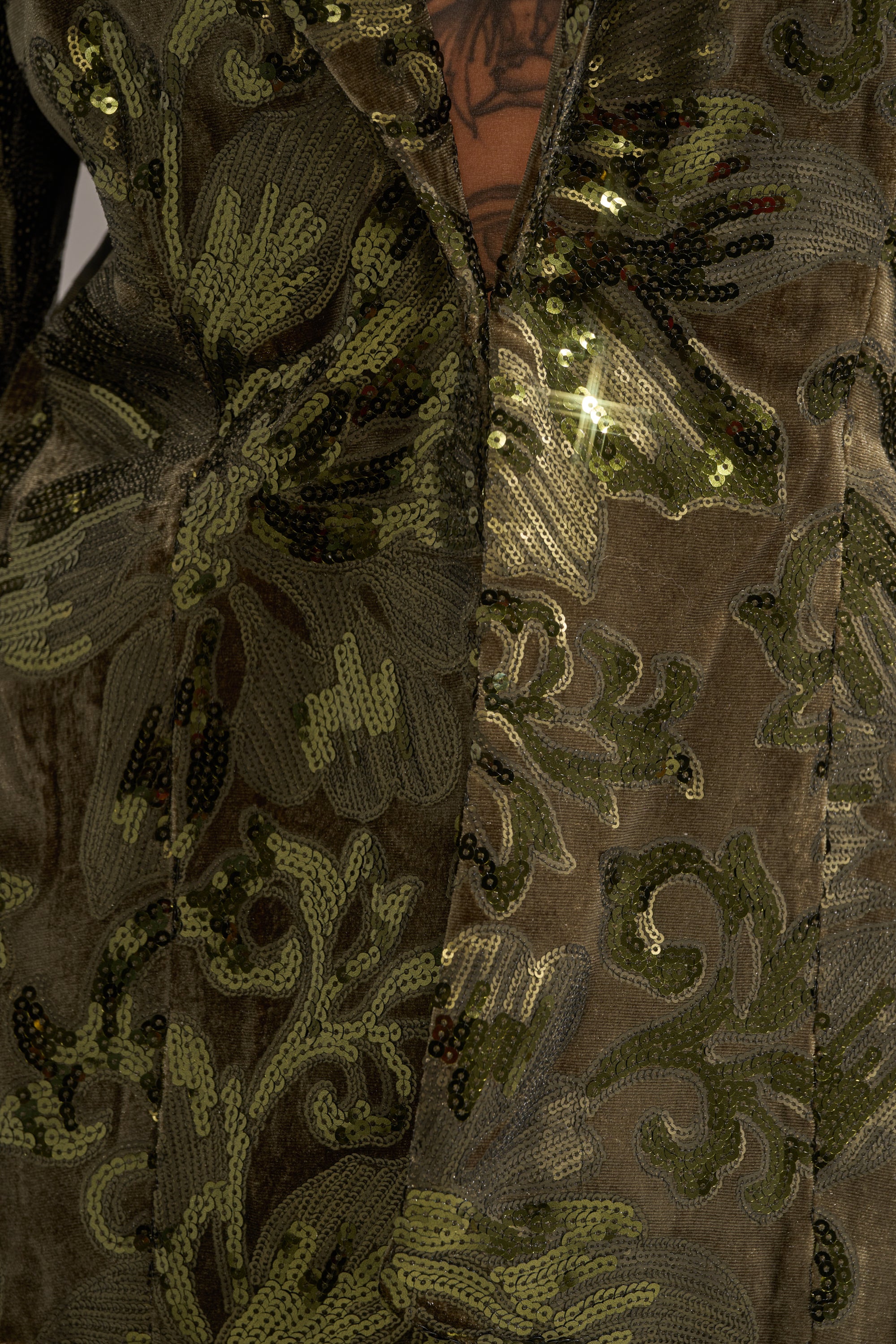 Close-up of the AURORA SEQUIN VELVET BLAZER, featuring intricate floral sequin patterns that catch the light, with a glimpse of a tattoo visible at the open neckline.