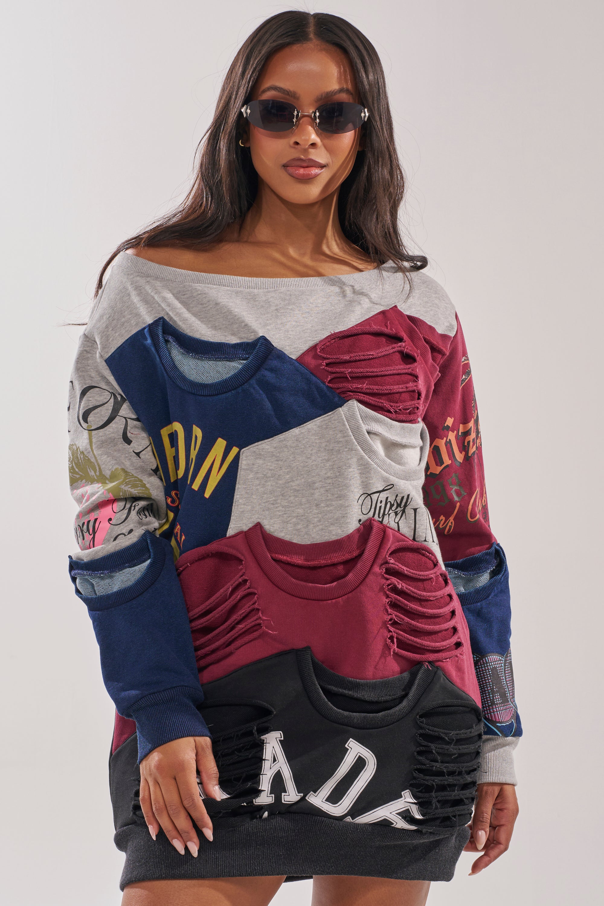 A woman in the TALK LATER OFF THE SHOULDER PATCHWORK DRESS, featuring colorful patchwork, printed text, and cut-out details, styled as an oversized mini dress with sunglasses, poses against a plain background. 0