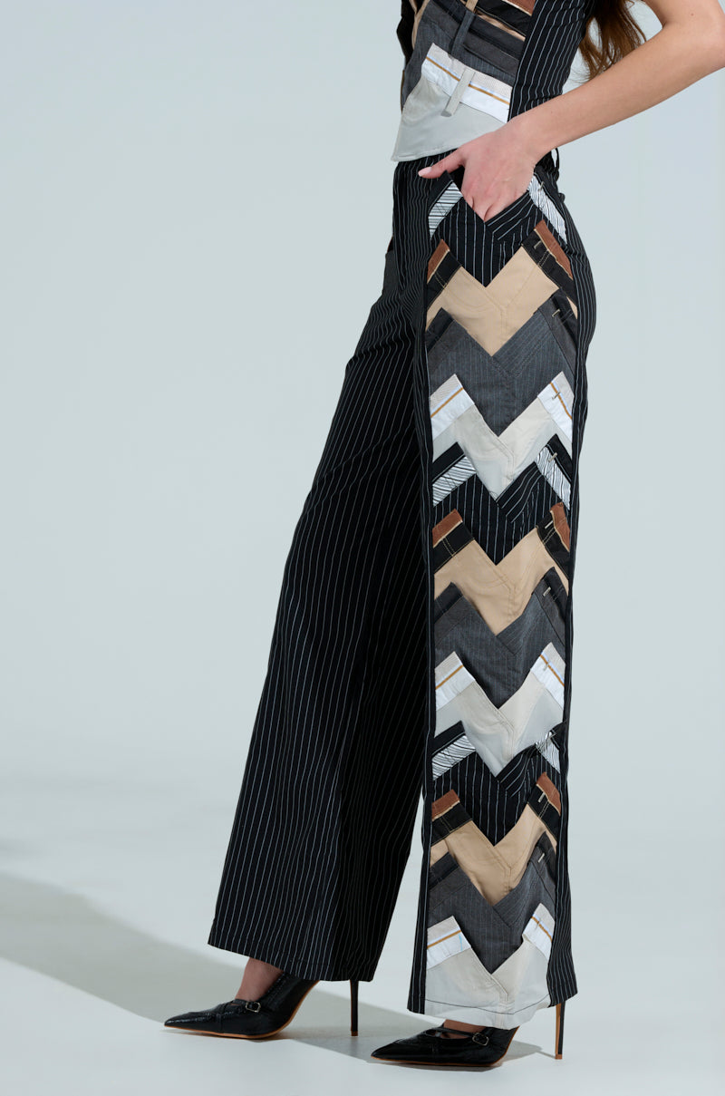 A person wearing STANDING ON BUSINESS LAYERED TROUSER with a side chevron pattern in beige, white, and gray tones perfectly captures the office chic style. The ensemble is completed with black pointed shoes and a top against a plain background for an elegant business-casual look.