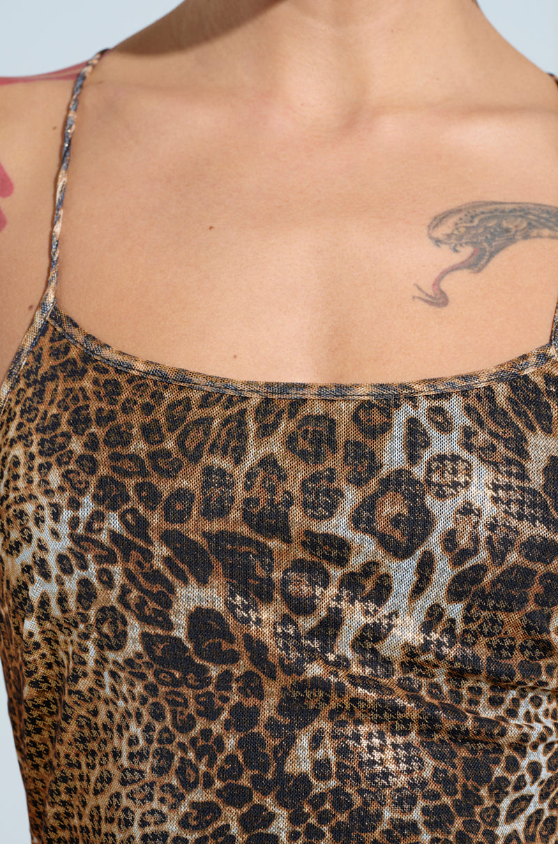 Close-up of a person wearing the FEELIN FINE LEOPARD PRINT JUMPSUIT with a snake tattoo visible on the shoulder, highlighting the curve-snatching silhouette. The neutral background emphasizes the design and pattern of this outfit.