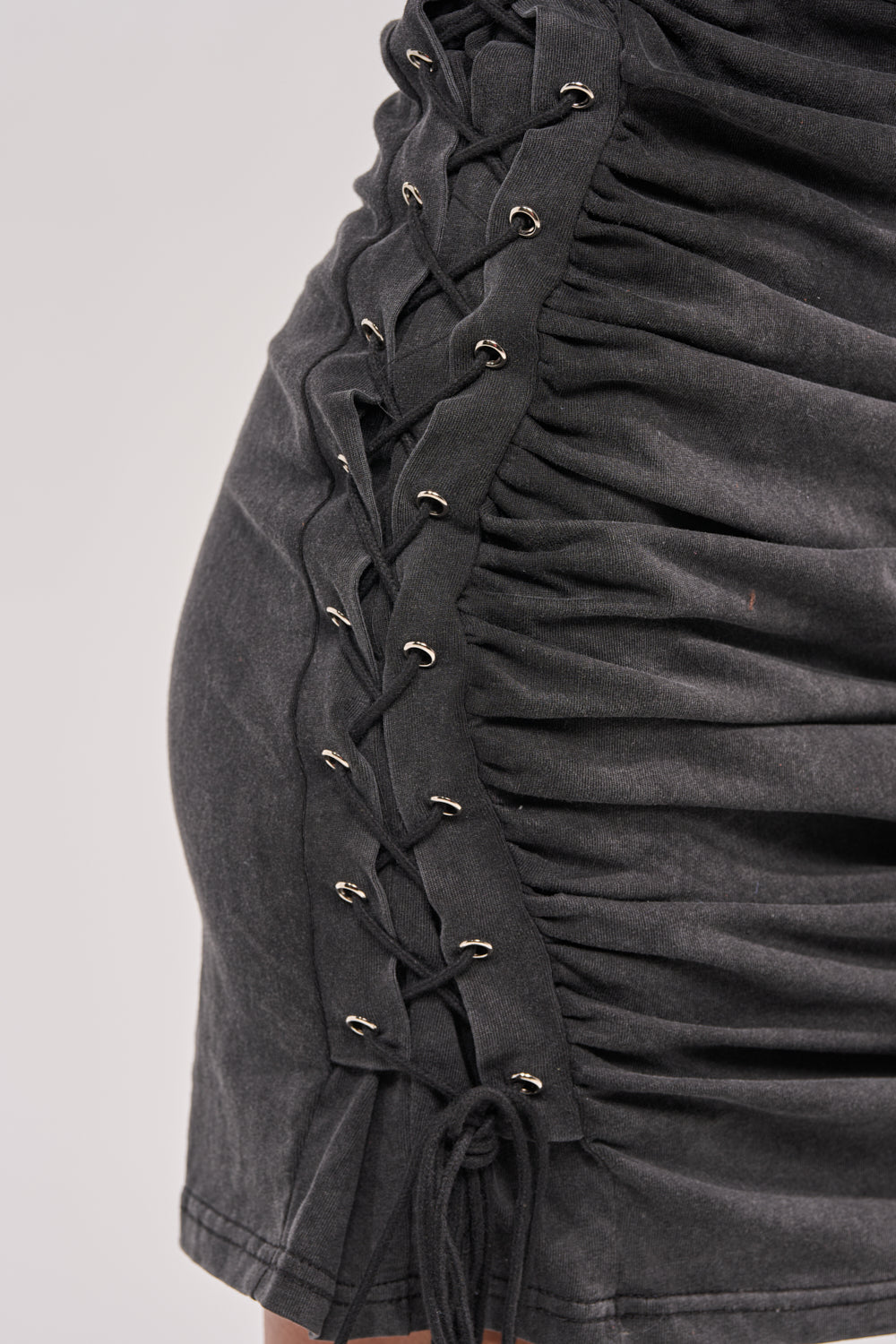 Close-up of the BUTTERFLY EFFECT MINI DRESS, a black ruched skirt with side lace-up detail featuring silver eyelets and black laces—ideal for an effortlessly stylish streetwear look. 11