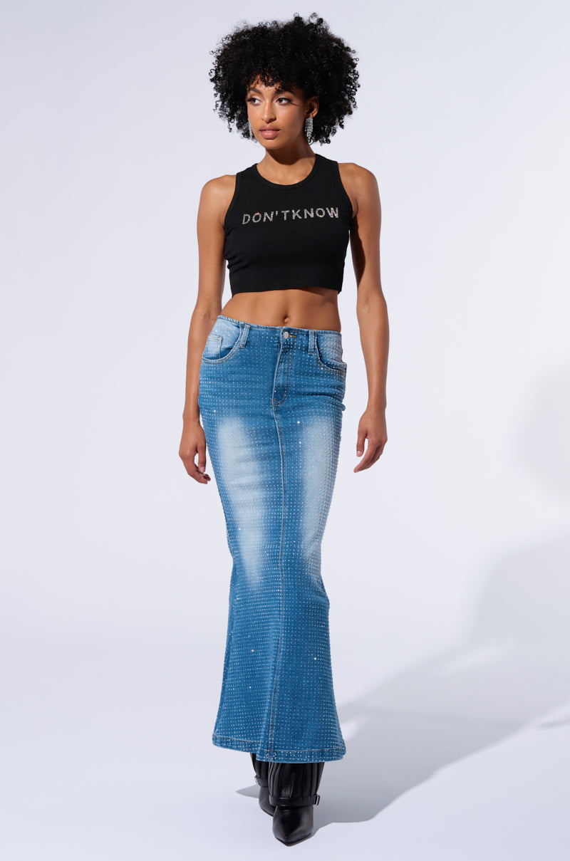 A person with curly hair is wearing a black crop top with "DON'T KNOW" text and the RICH GIRL ENERGY EMBELLISHED DENIM MAXI SKIRT featuring rhinestone detailing. They are also wearing black boots against a plain white background.