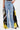 Wearing the DONT MESS WITH ME WIDE LEG DENIM PANT, a high-rise, light blue wide-leg jean with black lace and yellow mesh panels, paired with a small silver handbag.