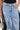A person wears DONT MESS WITH ME WIDE LEG DENIM PANT in light blue with a black top, one hand in their pocket and the other holding a small silver textured handbag.