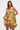 A woman wearing the LOVER GIRL BROCADE BUBBLE DRESS—strapless, yellow, with pink floral patterns—holds a gold clutch and looks at the camera against a plain light background.