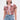 A woman wears large angular earrings and the BEACHY BLISS CROCHET SHORT SLEEVE BUTTON DOWN, featuring a lavender collar and zigzag pattern, paired with high-waisted, belted denim shorts against a plain white background.