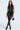 A woman in a stylish black outfit showcases a chic AKIRA Label 