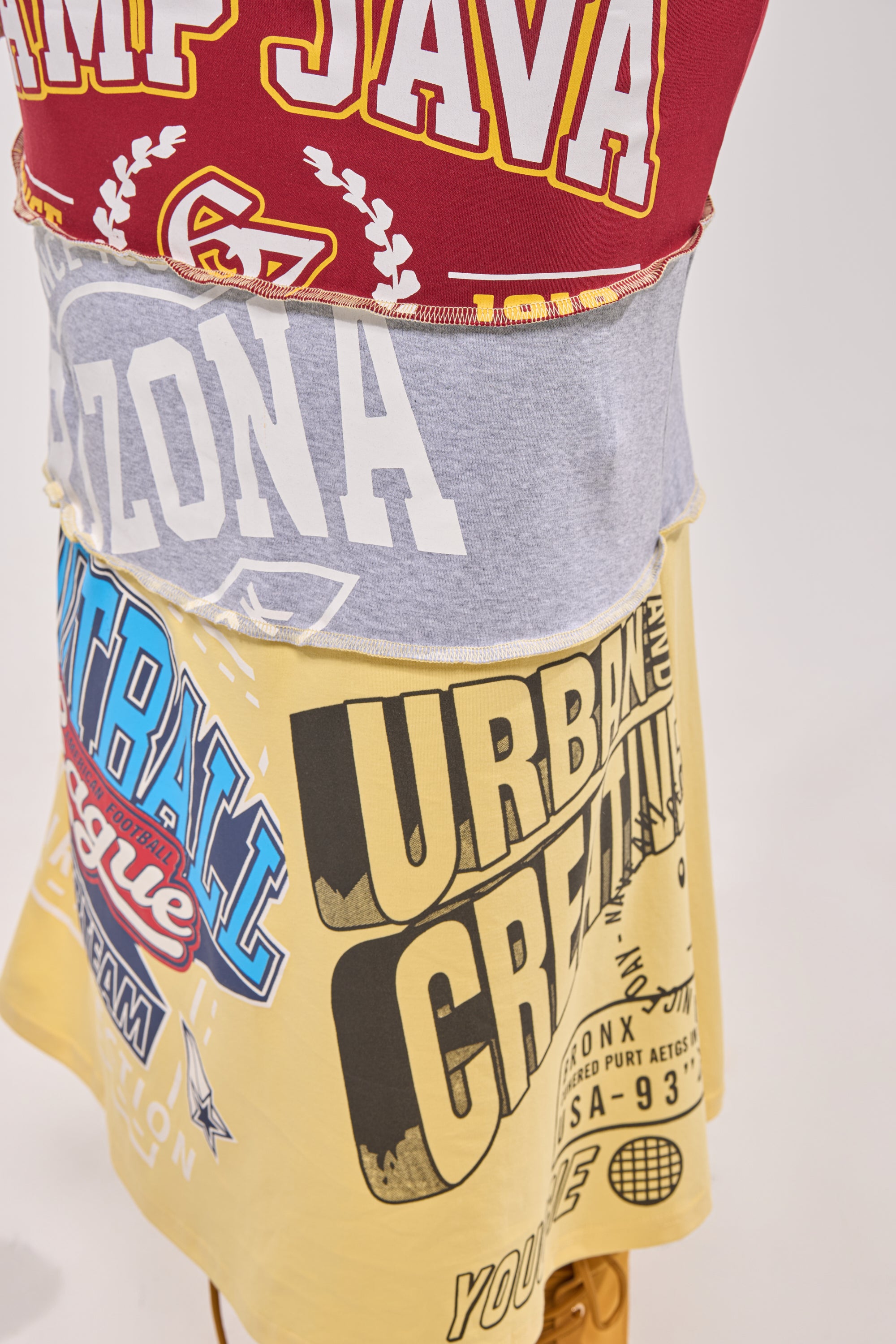 A close-up of the FULL RIDE PATCHWORK MAXI SKIRT, crafted from upcycled T-shirts in red, gray, blue, black, and yellow with sports and urban-inspired prints—ideal for making a bold statement courtside. 8