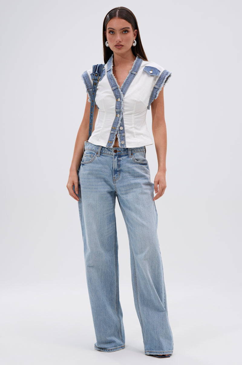 A woman with long straight dark hair, a neutral expression, and light blue wide-leg jeans wears the DENIM BABY BUTTON DOWN TOP—featuring denim trim and button details—while facing forward against a plain backdrop. 6