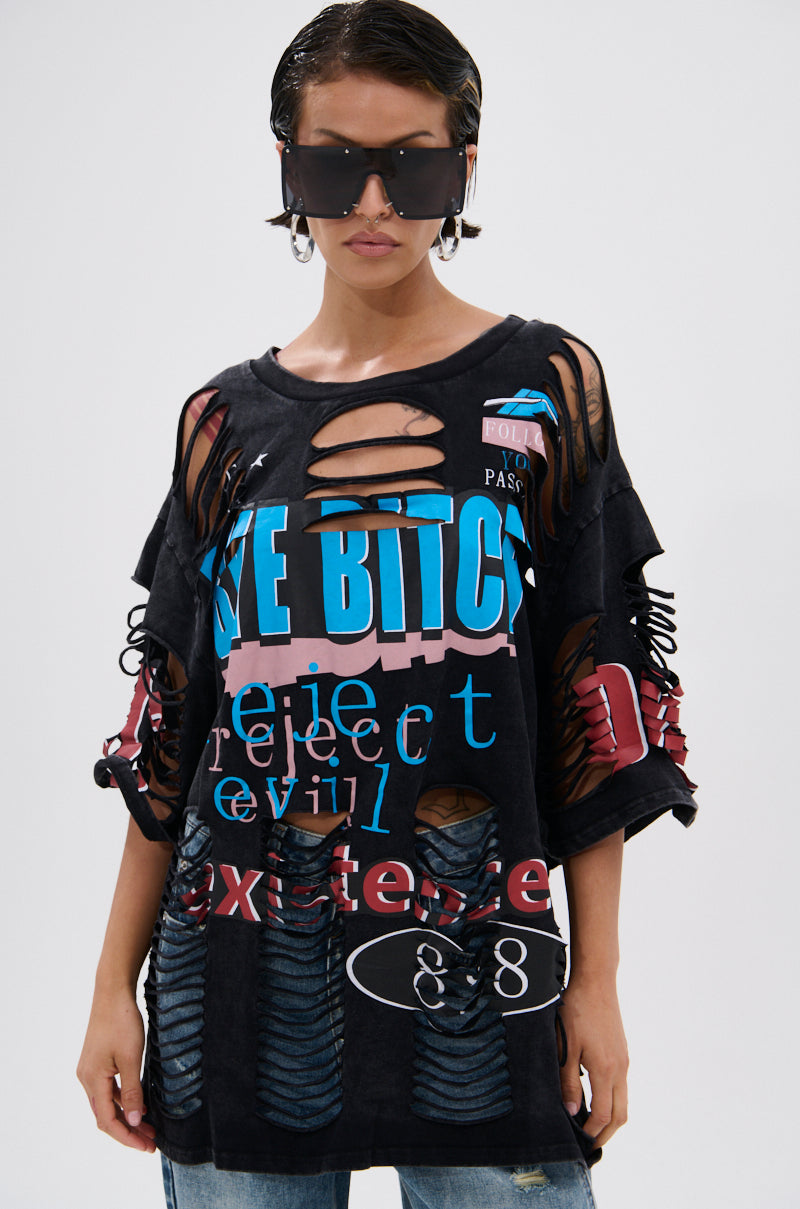A person in oversized black sunglasses and a BYE GIRL OVERSIZED DISTRESSED TEE—an oversized T-shirt with colorful bold text and graphic designs—faces forward against a plain background. 1