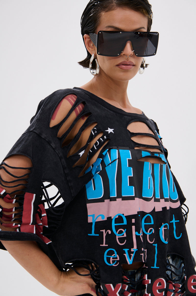A woman with slicked-back hair and large hoop earrings exudes confidence in oversized square sunglasses and the BYE GIRL OVERSIZED DISTRESSED TEE, featuring bold, colorful "BYE" text for a statement-making look. 5
