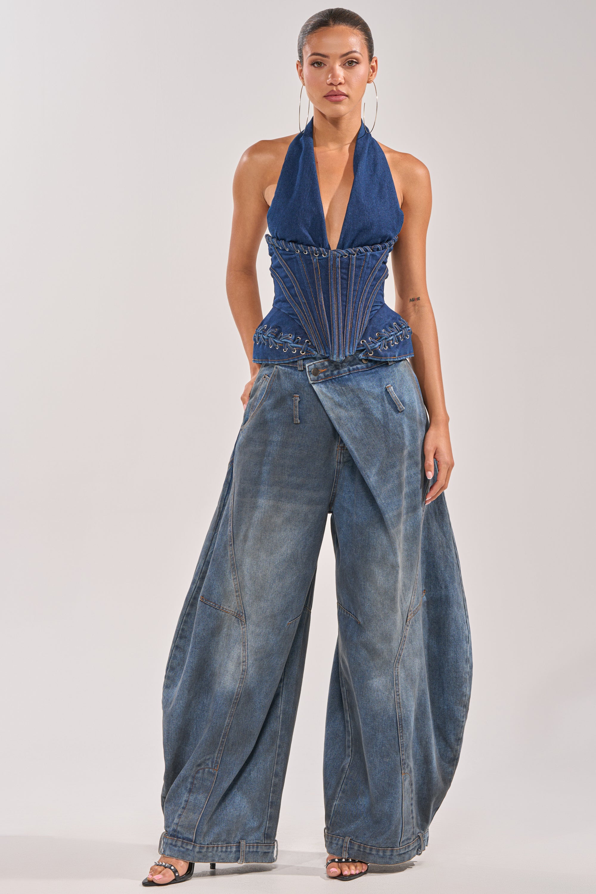 A woman in the NOT MY PROBLEM DENIM CORSET with decorative stitching and wide-leg draped denim jeans poses confidently against a light background, showcasing a western-inspired look. 5