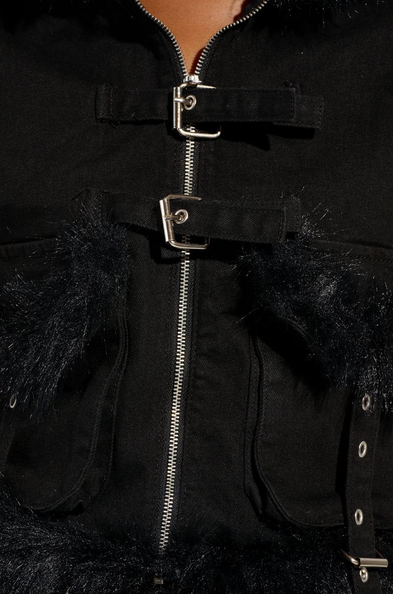 A close-up of the DELANEY FUR TRIM DENIM VEST highlights its cropped silhouette with a front zipper and two buckle closures, featuring luxurious faux fur detailing around the buckles and upper chest.