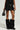 A person wearing the DELANEY FUR TRIM MINI SKIRT paired with a matching top, holding a small black handbag. The outfit is accessorized with black faux fur knee-high boots against a plain and neutral background.