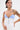 A person with short dark hair and tattoos models the KLYA CORSET, a strapless colorblock top with vertical stripes and decorative buttons, creating a structured silhouette against a plain white background.