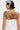 A person with a short black and white hairstyle wears a strapless KLYA CORSET top, revealing upper back and arm tattoos including a detailed portrait of a woman with snakes in her hair.