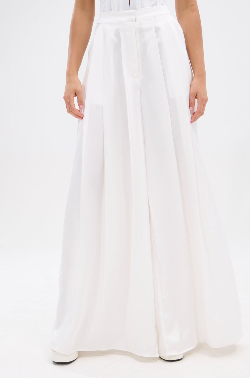 A person showcases the KYLA TROUSER, elegant satin trousers with a high-rise silhouette, against a plain white background. Only the lower half of their body is visible. 1