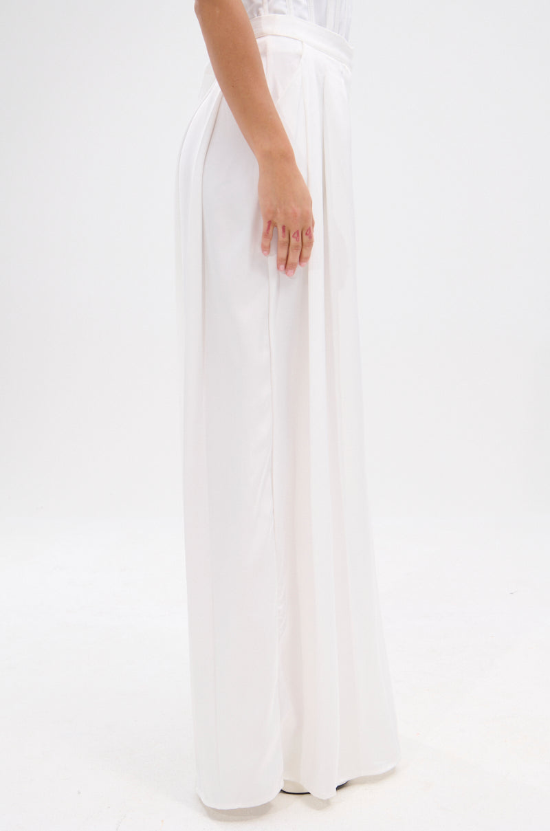 A person, shown from the waist down against a plain white background, models the KYLA TROUSER—high-rise, wide-leg silhouette satin trousers—paired with a sleeveless white top. 3
