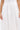 A person models the KYLA TROUSER, a white high-waisted, pleated pant with a chic high-rise silhouette, shown from waist to mid-thigh with arms relaxed at their sides.