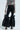 Wearing the chic Lily Trouser with Bow in Black and a black and white striped top, accessorized with a small purse and high heels, they make a bold fashion statement.