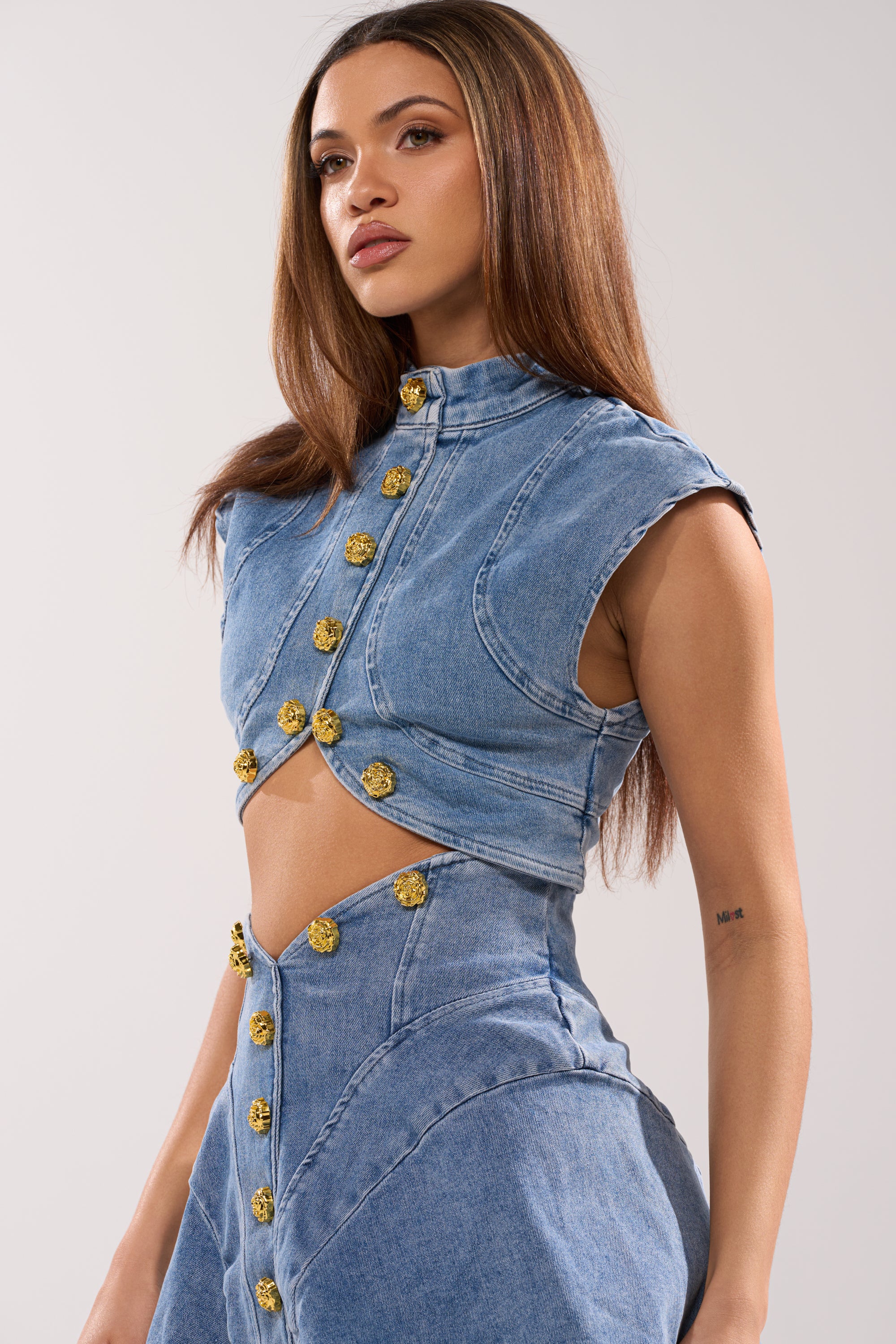 A woman with long straight hair wears the GIVE IT TO ME BABY DENIM BUTTON DOWN and matching high-waisted skirt, both with unique seams, standing against a plain light background. 5
