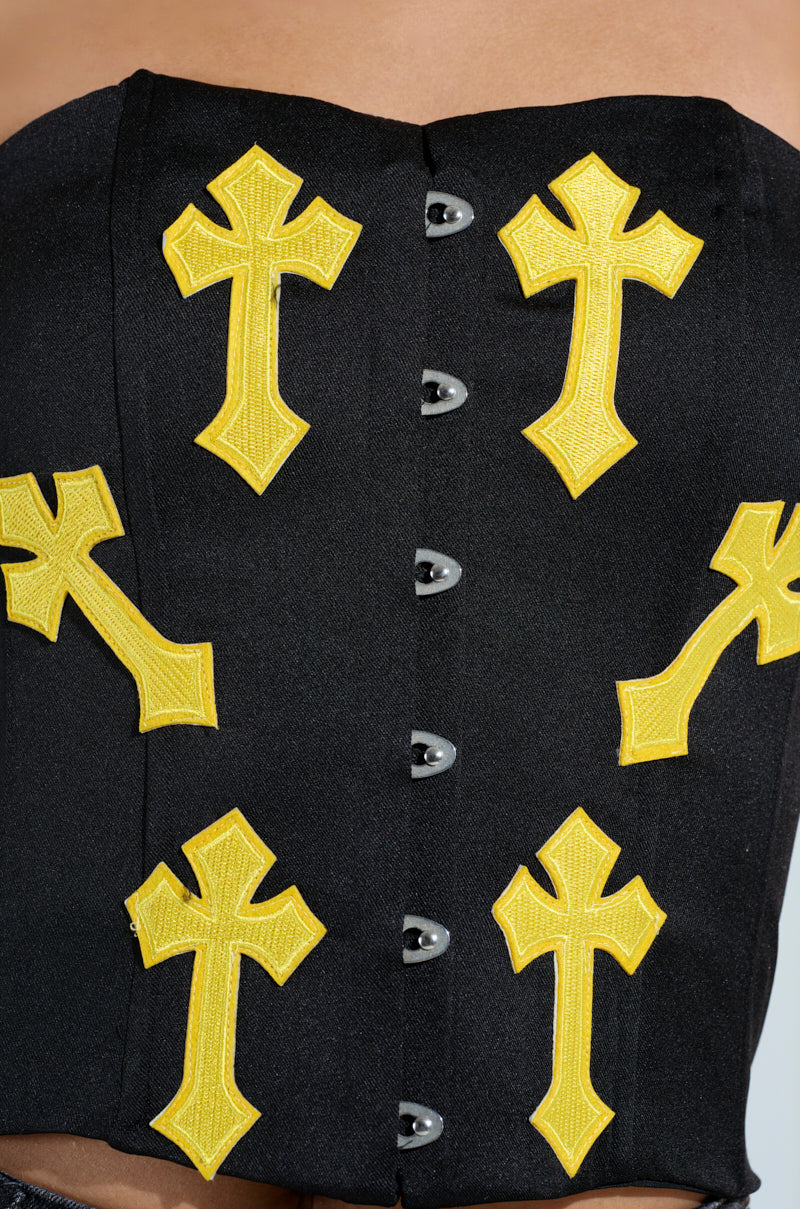 Close-up of the JAYLIN CROSSED CORSET, a chic black strapless corset with multiple yellow cross-shaped appliqués. It features silver front fastenings, blending edgy and gothic fashion elements.