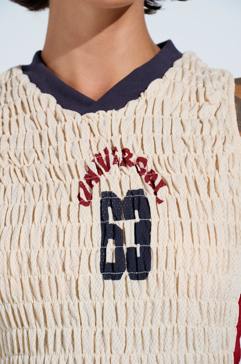 Close-up of a person wearing the ADDICTED RUCHED JERSEY TOP in cream with navy collar, featuring sporty red "CAVIA R GAL" text and a navy "68" on the front.