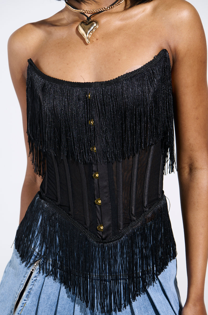 Dressed in a black fringed off-shoulder FLAPPER GIRL CORSET TOP with gold buttons and boning, a choker necklace with a gold heart, and a light blue denim slit skirt, this outfit perfectly blends modern and vintage-chic styles.