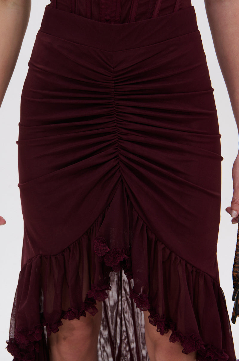 A close-up of the LOVELY DAYS MESH HIGH LOW SKIRT featuring center ruching, a high-low hem, lace trim at the bottom, and gathered mesh fabric for a layered look. The person’s hands rest at their sides. 6