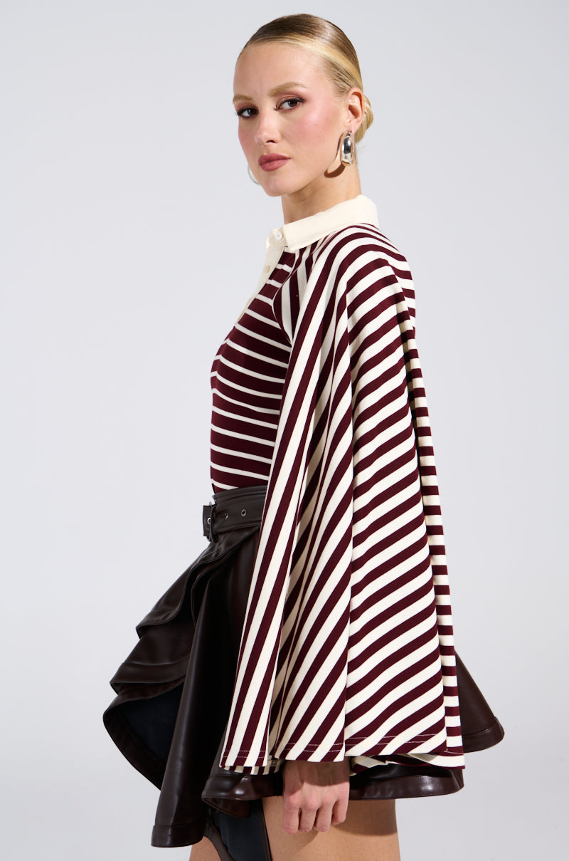 A woman in profile wears the ALMA STRIPE COLLARED BODYSUIT, a vintage-cool maroon and white striped piece with cream accents, styled with a high-waisted black ruffled skirt. She has slicked-back hair and statement earrings.